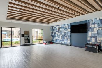 a large living room with wood floors and a large screen tv on the wall  at Century West Pryor, Lee's Summit, MO